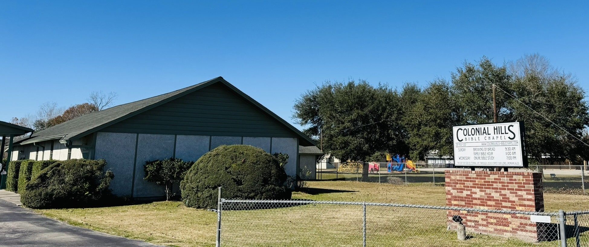 Colonial Hills Bible Chapel and its sign on Henry Road under a clear blue Texas sky.