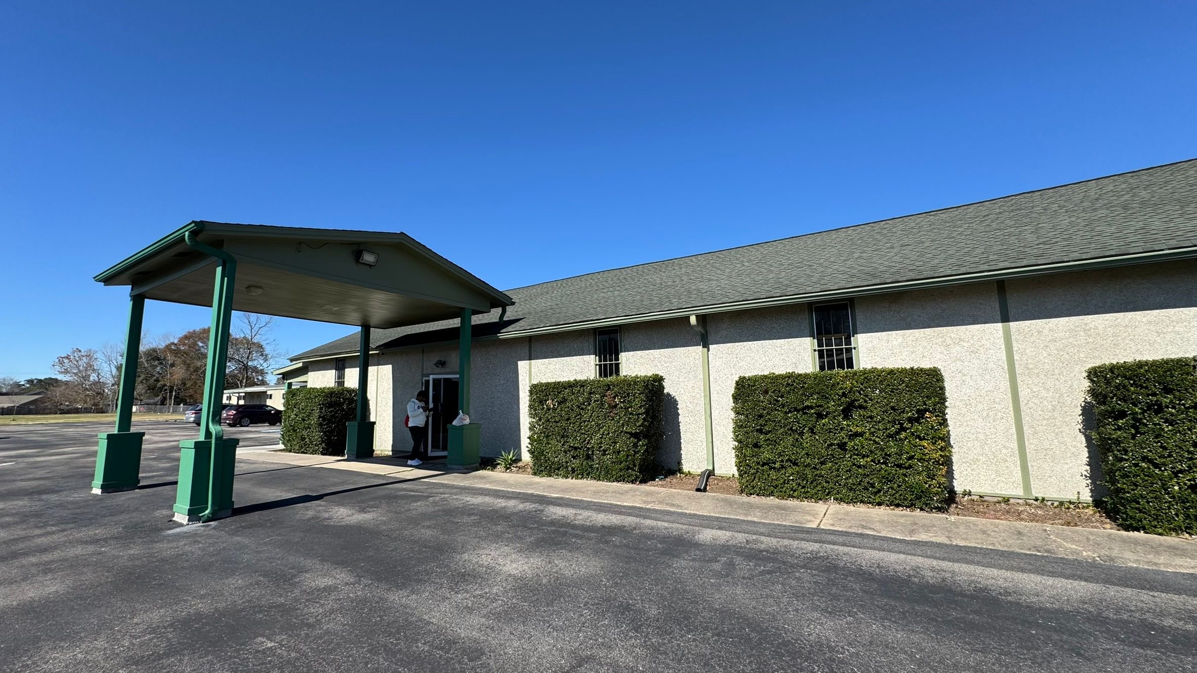 The front entrance of Colonial Hills Bible Chapel with its green covered portico under a blue sky
