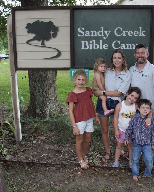 Keith and Callie Munsterman with their children at the Sandy Creek Bible Camp sign